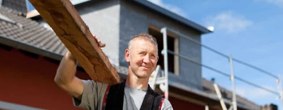 a man on a nice day holds a piece of wood and ponders about complacency in the work place