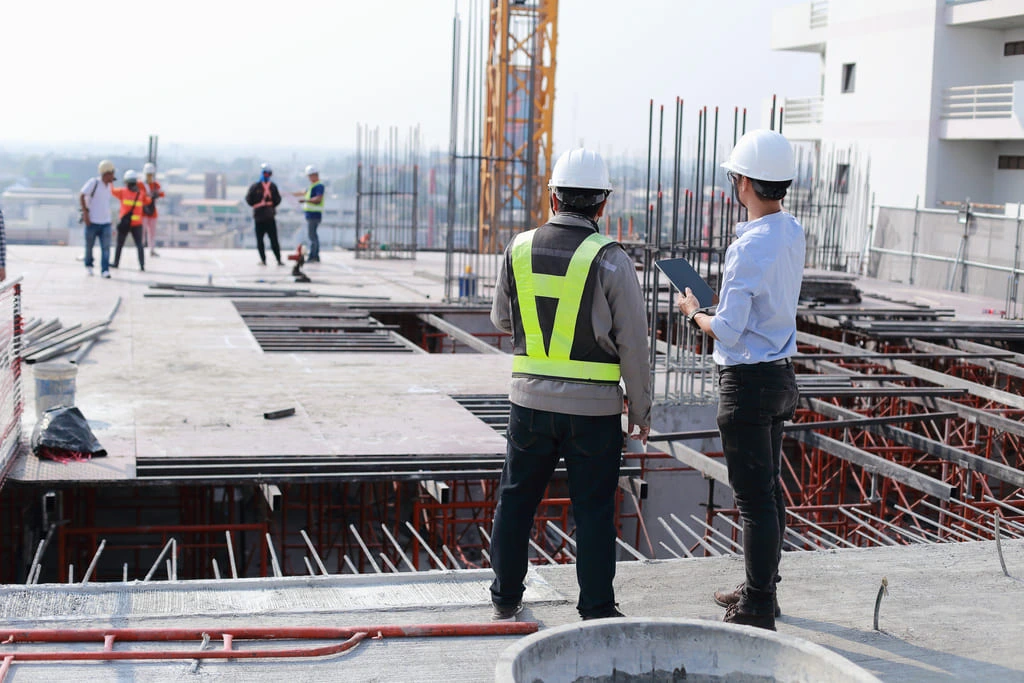 Safety professionals on a construction site applying Behavior-Based Safety by observing and discussing worker behavior.