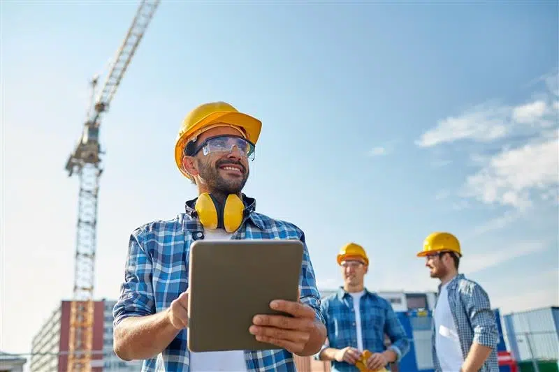 Construction worker using a tablet symbolizing real-time digital audits that drive site-wide safety improvements.