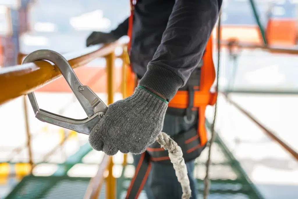 Worker securing a safety harness clip to scaffolding as part of a proactive hazard prevention effort.