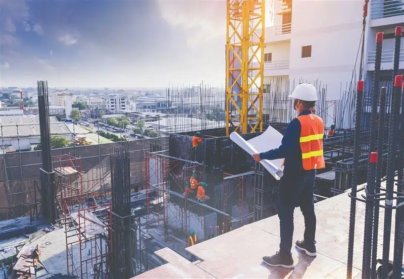 Construction site supervisor reviewing blueprints on a high-rise structure.