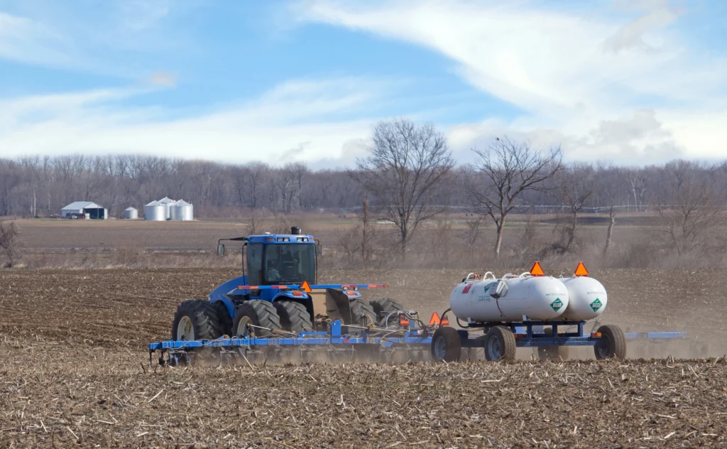 Tractor towing nurse tanks of anhydrous ammonia across a field for fertilizer application.
