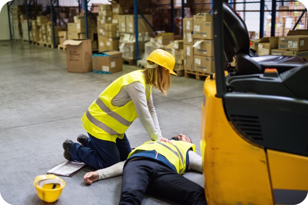 Employee calling emergency services while a coworker performs CPR on an injured worker.