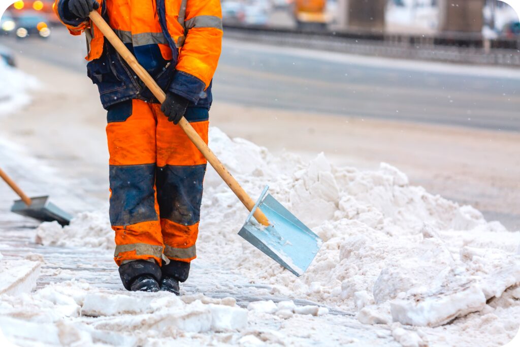 Maintenance staff applying ice melt on a slick pathway at night to improve traction and prevent injuries.