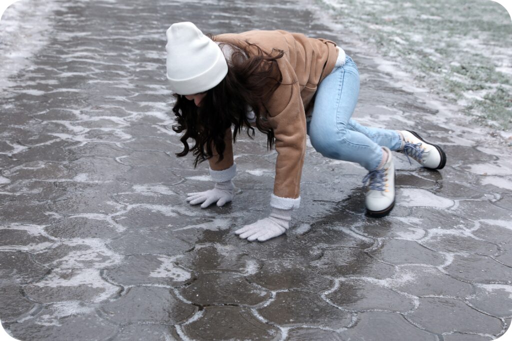 Employee slipping on an icy walkway, illustrating winter slip, trip, and fall hazards at ground level.