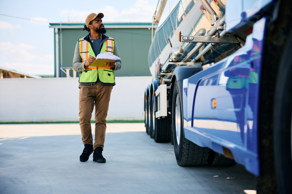 A fleet supervisor reviewing inspection notes while examining a commercial vehicle.
