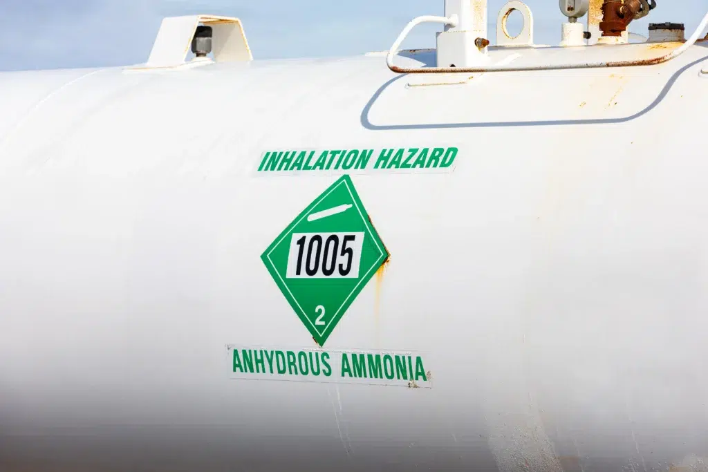Anhydrous ammonia storage tank with UN 1005 inhalation hazard placard and green gas label.