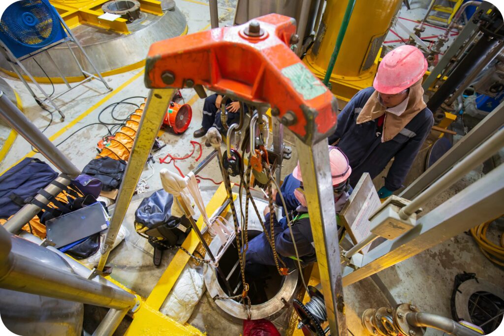 Trained entrant entering confined space under supervision with protective equipment.