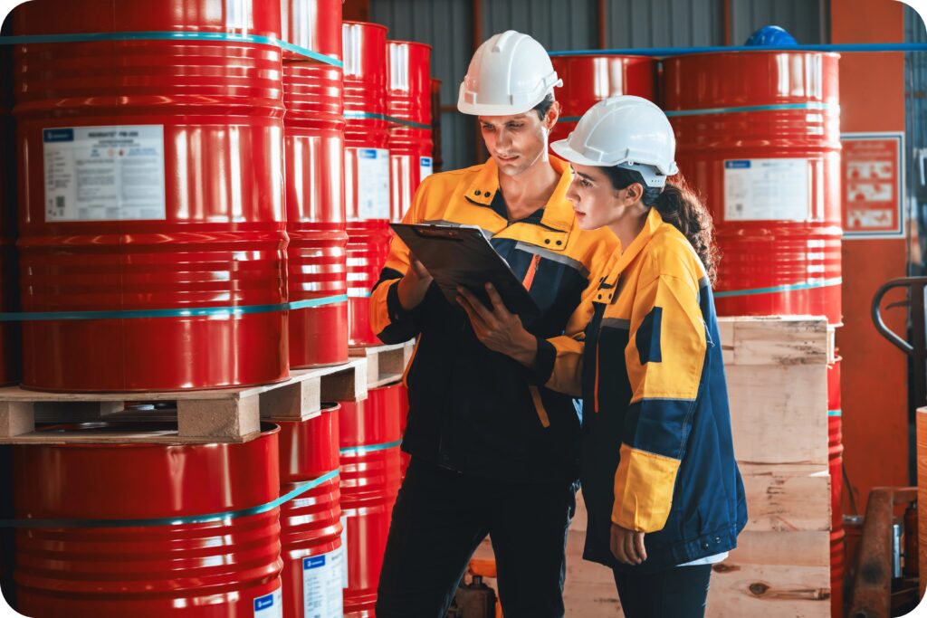 Safety inspectors reviewing hazardous chemical drums during WHMIS compliance audit.