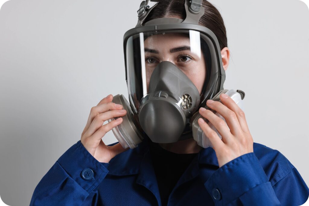 Employee checking fit and seal on a full-face respirator before exposure to workplace airborne hazards.