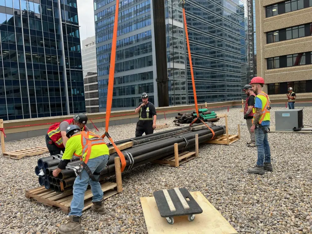 Crew members working together on a rooftop construction site surrounded by tall glass buildings.