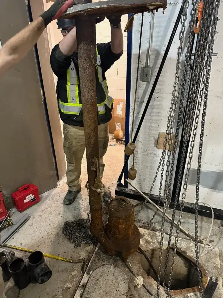 Two workers handling rebar and construction materials indoors while wearing protective gear.