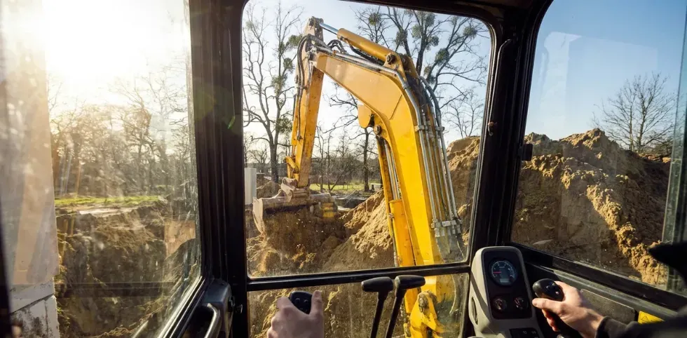 Mini excavator operating on uneven ground, highlighting stability and load control covered in excavator safety training.